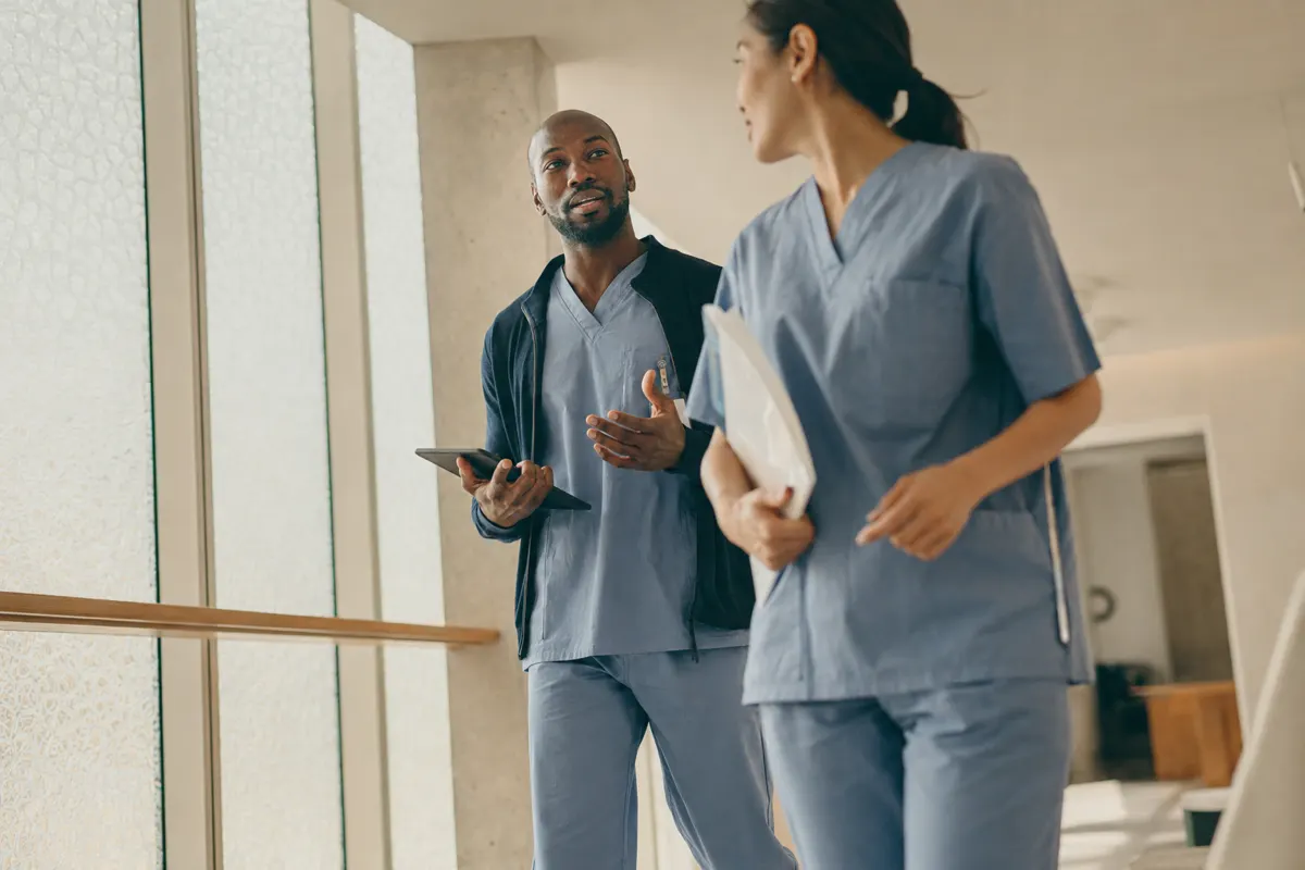 Two clinicians talking in a clinic corridor, away from the phones